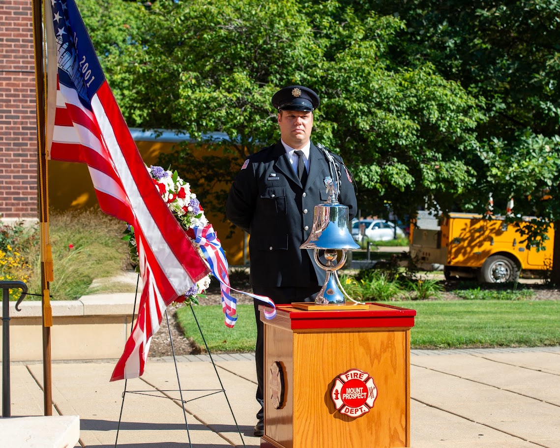 911 Ceremony Fireman standing behind silver bell.